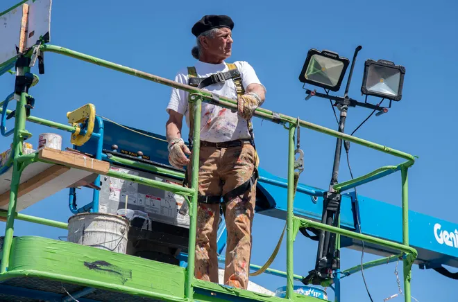 Artist standing on a lift while working on the mural.