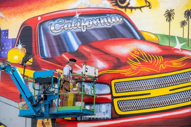 The mural in progress with lift equipment nearby.