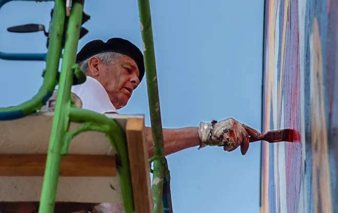 Close-up of an artist painting a mural detail.