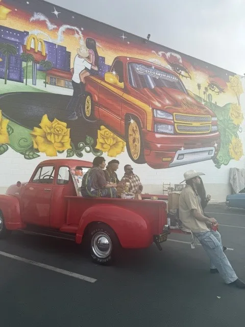 Red classic car parked in front of the mural.