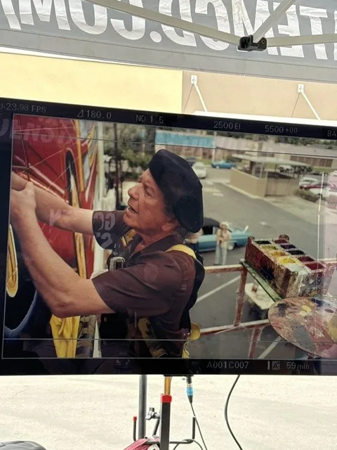 Artist painting a close detail near the mural.
